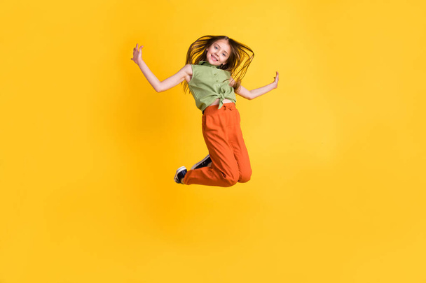 Longitud completa tamaño del cuerpo foto niña saltando descuidado feliz aislado vibrante color amarillo fondo - Foto, Imagen