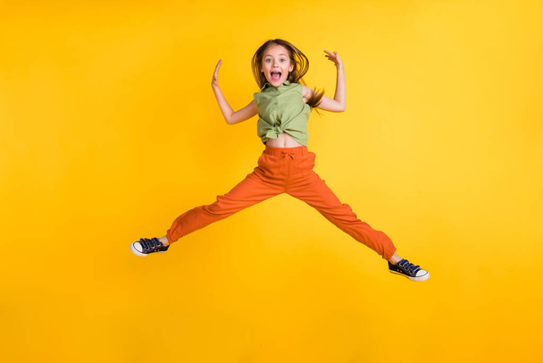 Volledige foto van funky blond klein meisje spring slijtage top broek geïsoleerd op gele kleur achtergrond - Foto, afbeelding