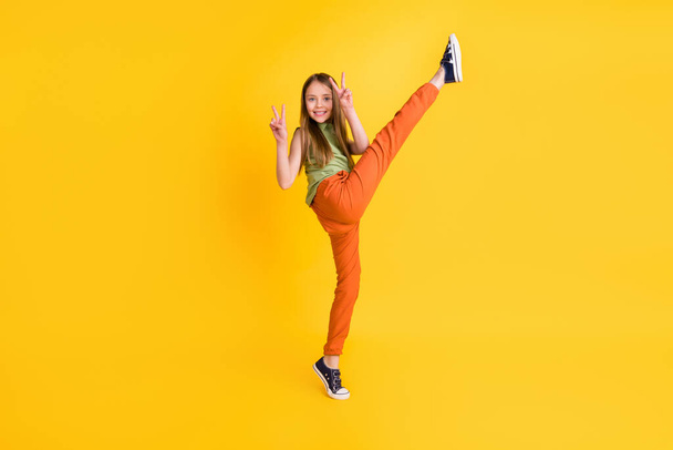 Full body photo of funny blond small girl do sport v-sign wear blouse trousers isolated on yellow color background - Фото, зображення