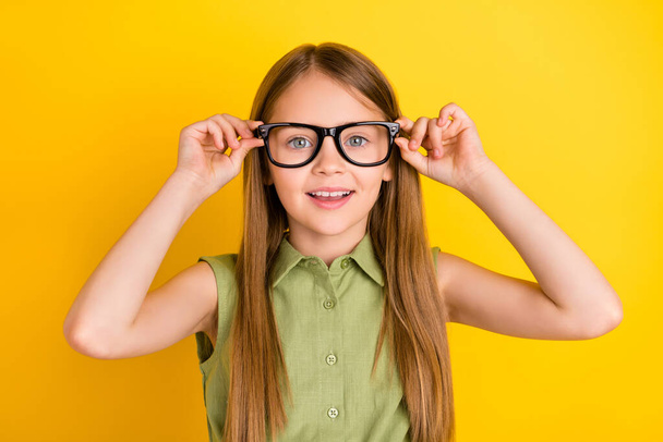 Photo of nice blond little girl hold eyewear wear khaki blouse isolated on yellow color background - Foto, Imagem