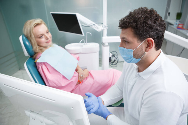 Erfahrener Zahnarzt arbeitet in seiner Klinik und spricht mit mündigen Patienten - Foto, Bild
