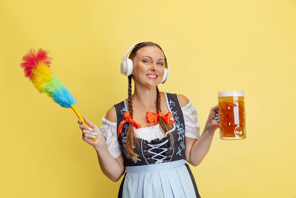 Comic portrait of beautiful Oktoberfest woman, waitress wearing a traditional Bavarian or german dirndl isolated on yellow studio background. - 写真・画像