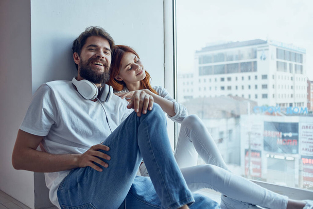 una joven pareja se sienta cerca de la ventana con auriculares juntos apartamentos - Foto, imagen