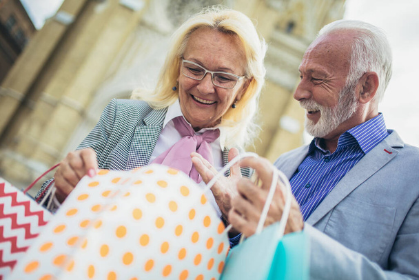 šťastný starší pár s jejich nákupy nákupy za slunečného dne - Fotografie, Obrázek