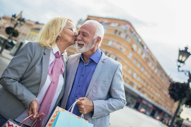 Heureux couple d'âge mûr marchant avec leurs achats par une journée ensoleillée
 - Photo, image