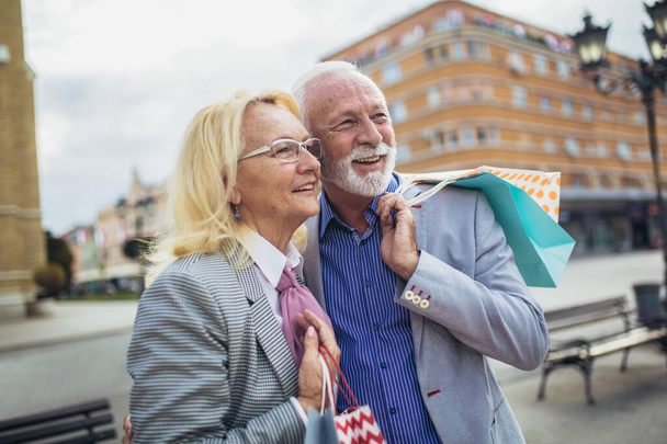 szczęśliwy starsza para spaceru z centrum zakupów w słoneczny dzień - Zdjęcie, obraz