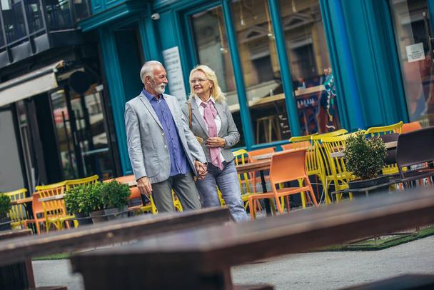 Mature married couple are walking through a city together. - Photo, Image