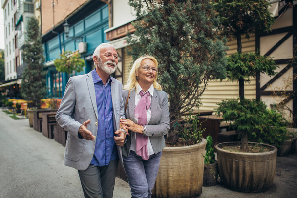 Зрелая супружеская пара гуляет по городу вместе. - Фото, изображение