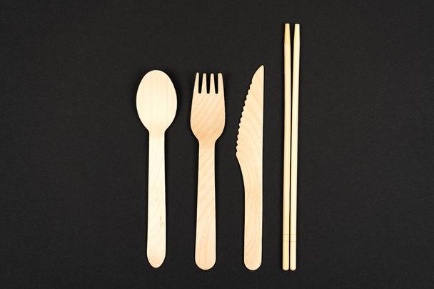 Eco ruokailuvälineet puusta ja bambusta. Sushi haarukat, lusikat ja syömäpuikot paikka tekstiä mustalla pohjalla. - Valokuva, kuva
