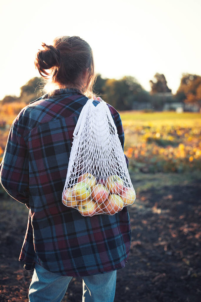 girl holds  bag from macrame  with juicy apples. aesthetics of rural lif - Foto, afbeelding