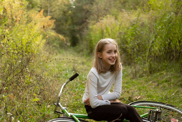 Hermosa chica adolescente caucásica en una bicicleta en el bosque en la naturaleza.  - Foto, imagen