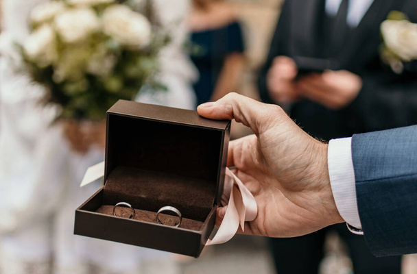 Close-up image of hand holding box with wedding rings. - Foto, Imagem