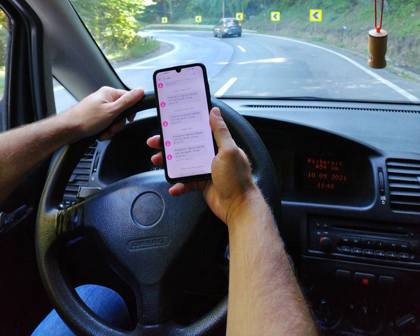 Мужчина пользуется мобильным телефоном, когда водит машину. Еще один автомобиль на дороге впереди. Опасное вождение и высокая вероятность ДТП - Фото, изображение