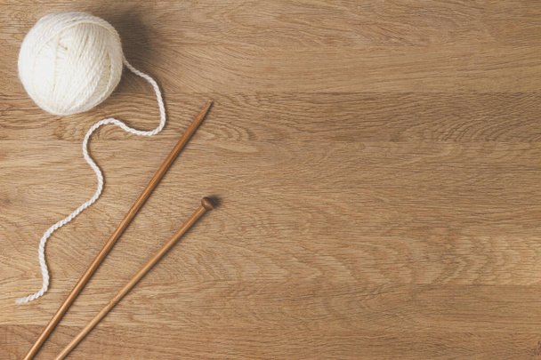 Wooden knitting needles and ball of yarn on wood background. Top view - Фото, изображение