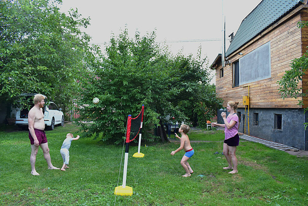 Perhe pelaa lentopalloa gazanilla kotona.. - Valokuva, kuva
