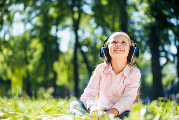 Girl in summer park listening music - Foto, imagen