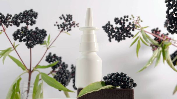 Natural medicine from berries on a white background copy space, homeopathy, a branch of black elderberry with a medicinal spray can - Valokuva, kuva