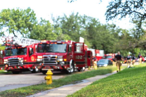 Bombero borroso abstracto rescate accidente de incendio en casa residencial en los suburbios Dallas, Texas, Estados Unidos. Fila de camión de bomberos con escaleras y bomberos en funcionamiento - Foto, Imagen