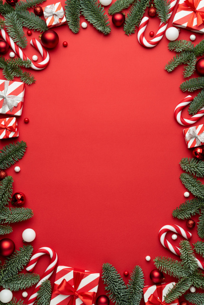 Fondo rojo con cajas de regalo de Navidad y marco de decoraciones de Navidad. Colocación plana, vista superior y espacio de copia para texto - Foto, imagen