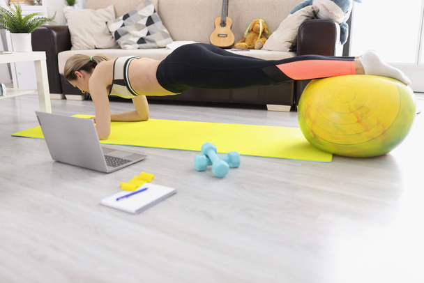Young athletic woman doing plank on fitball at home - Fotó, kép
