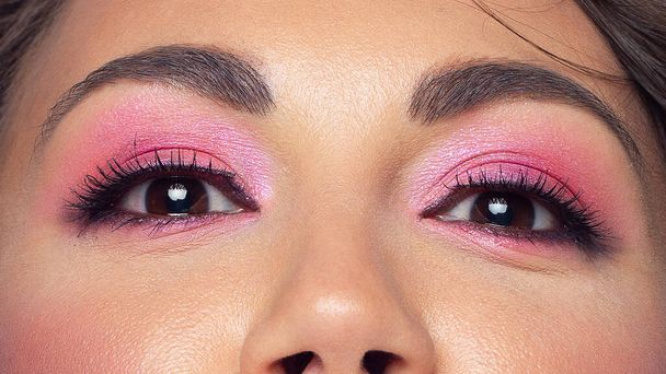 Beautiful macro of expressive brown eyes with fashionable pink smoky shadows, extremely long eyelashes. Cosmetology, eyebrow correction, eyelash extensions, makeup, cosmetics, eyesight, contact lenses - Photo, Image