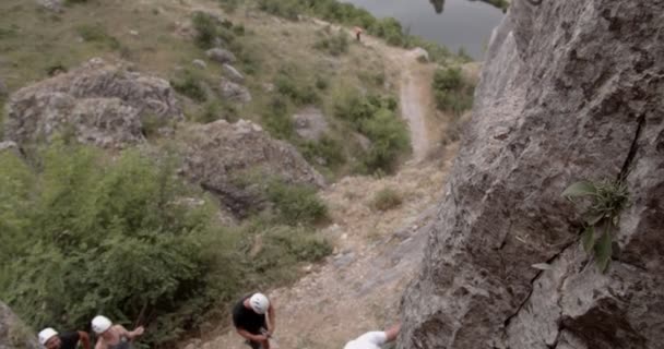 Knap en fit man bereidt de grote rots voor zodat de anderen het kunnen beklimmen. - Video