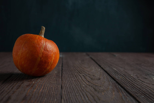 Pumpkin on wooden table in dark mood with copy space. - Photo, image