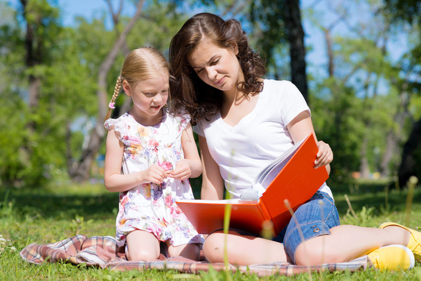 girl and a young woman reading a book together - Foto, Imagem