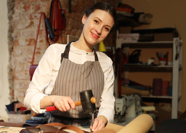 young woman works in a workshop, sews leather bags - Zdjęcie, obraz