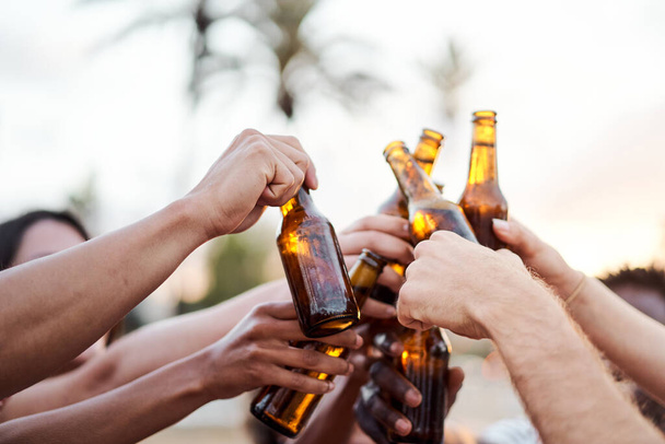 Dışarıda bira eşliğinde tezahürat yapan bir grup arkadaşın ellerini yakın tut. Yaz kavramı, arkadaşlar, gün batımı, kutlama, - Fotoğraf, Görsel
