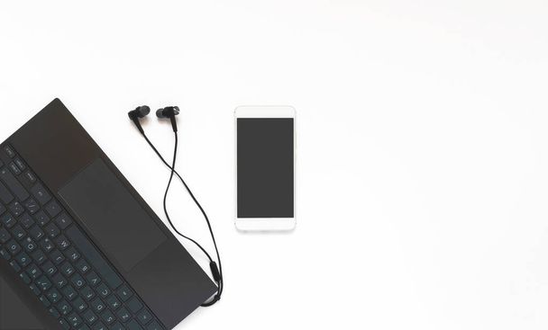 Laptop, headphones and phone on a white background. Minimum working space. Top view, flat layer - Φωτογραφία, εικόνα