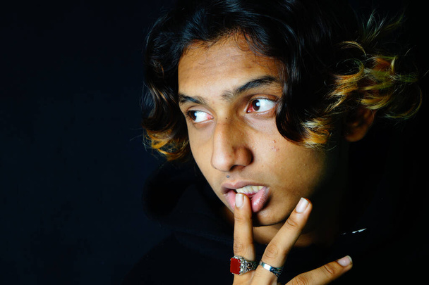 A közeli kép egy elegáns indiai jóképű férfi visel gyönyörű gyűrűk pózol a sötét háttérben - Fotó, kép