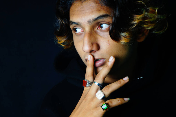 A closeup of a stylish Indian handsome male wearing beautiful rings posing on the dark background - Foto, Bild