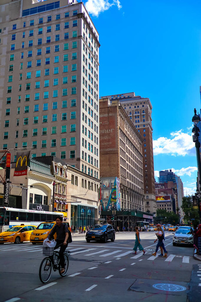 NEW YORK CITY, UNITED STATES - Jul 27, 2021: A vertical shot of a bustling street with yellow taxi cabs driving by skyscrapers in New York, United States - Photo, Image
