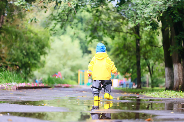 yellow raincoat boy look, autumn seasonal walk in the park - Foto, imagen