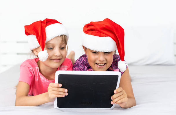 Aufgeregte kleine Geschwisterkinder haben Spaß beim gemeinsamen Surfen auf modernen Tablet-Geräten. Glückliche kleine Mädchen Kinder sehen Video auf Pad-Gerät, genießen Familie Winterurlaub zu Hause. - Foto, Bild