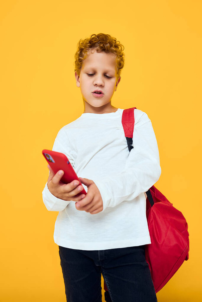 Cheerful young boy talking on the phone with a school backpack Studio learning concept - Foto, imagen