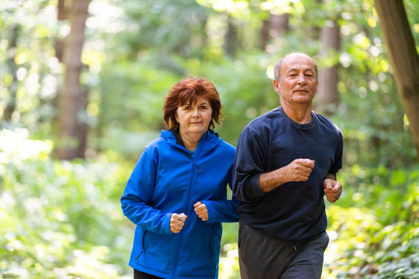 Glückliches Seniorenpaar läuft gemeinsam im Park - Foto, Bild