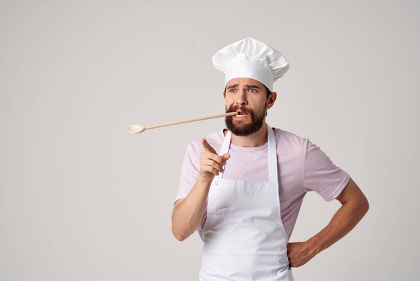 bearded male chef in uniform spoon in teeth working in a restaurant - Photo, image