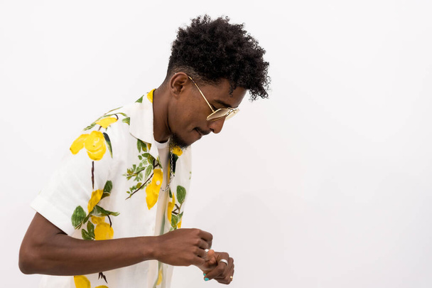 A young Cuban man in a floral shirt and glasses smiling and dancing on a white background, copy and paste space - Фото, зображення