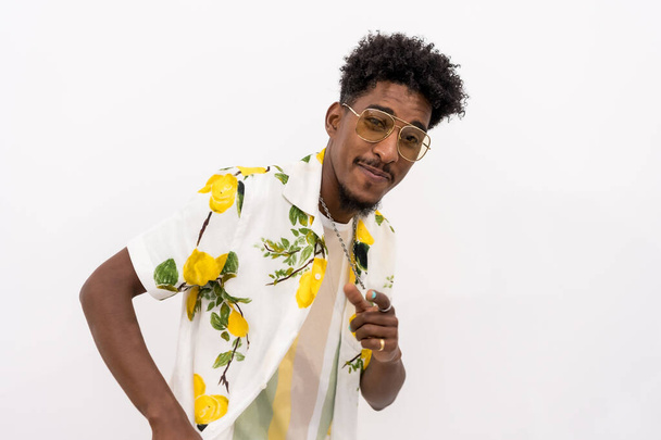 A young Cuban man with a white and green flower shirt, glasses, smiling and dancing on a white background, copy space and paste - Фото, зображення