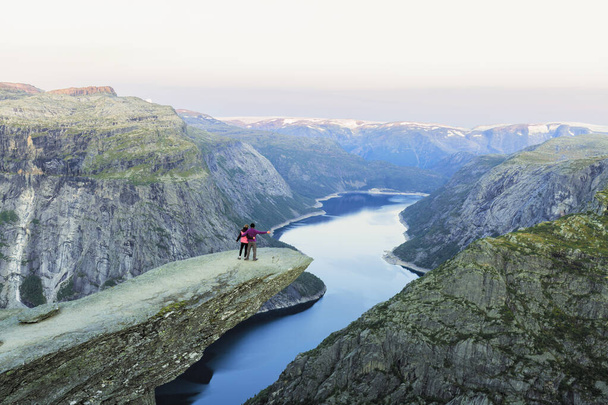 カップル男性と女性トロールトゥンガ崖の手の山愛と旅行の感情ライフスタイルの概念を調達した。ノルウェーのアクティブな冒険休暇を一緒に旅行する若い家族 - 写真・画像