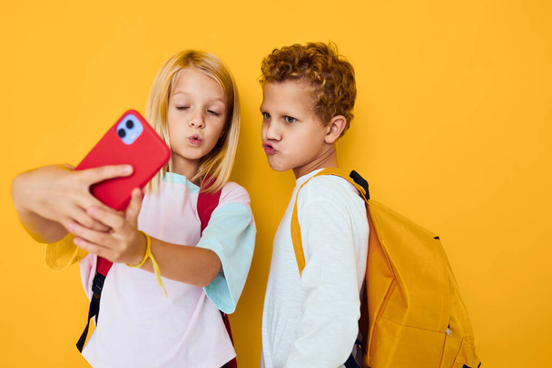 χαριτωμένα παιδιά με σχολικά σακίδια τηλεφωνική επικοινωνία ψυχαγωγία Studio εκπαίδευση έννοια - Φωτογραφία, εικόνα