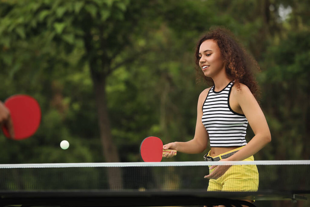 Young African-American woman playing ping pong outdoors - Фото, зображення