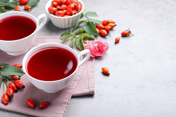 Fresh rose hip tea and berries on light table. Space for text - Foto, afbeelding
