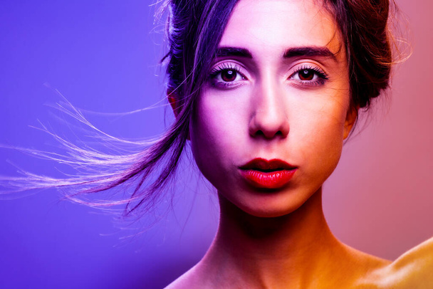 Beautiful brunette girl studio portrait. Neon lights. Serious face expression. - Photo, Image
