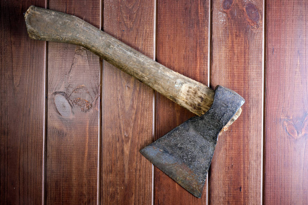 Old rusty blunt ax on dark brown wooden background close-up - Foto, Imagem