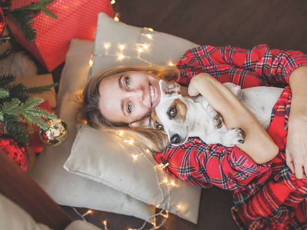 Happy woman with dog on Christmas tree background. Female at home - Photo, image