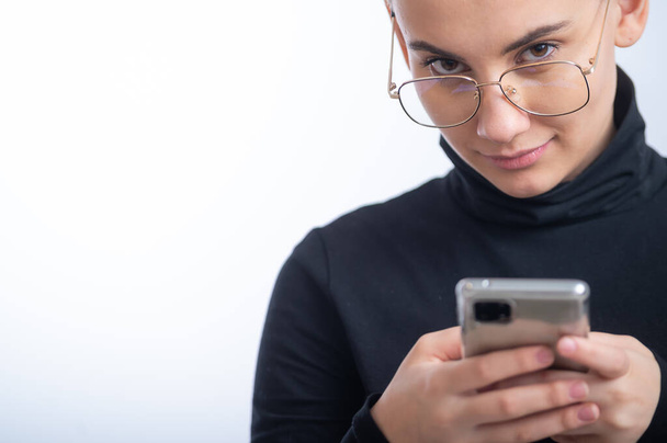 Young caucasian woman with short hair uses a smartphone on a white background. - Foto, Imagem