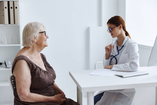 γυναίκα ασθενής που μιλάει σε ένα στηθοσκόπιο γιατρού - Φωτογραφία, εικόνα